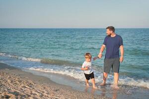 padre figlio la spesa tempo insieme mare vacanza giovane papà bambino poco ragazzo a piedi spiaggia foto