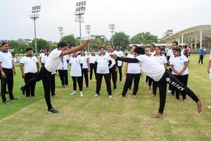 nuovo delhi, India, giugno 21, 2023 - gruppo yoga esercizio sessione per persone a yamuna gli sport complesso nel delhi su internazionale yoga giorno, grande gruppo di adulti frequentando yoga classe nel cricket stadio foto