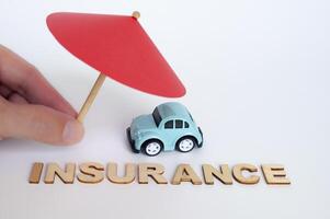 assicurazione testo con giocattolo auto e ombrello sfondo. auto assicurazione concetto foto