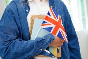 apprendimento inglese, asiatico adolescenziale alunno Tenere libro con bandiera per linguaggio programma formazione scolastica. foto