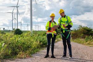 Due uomini nel sicurezza Ingranaggio siamo in piedi su un' strada vicino un' campo di vento turbine foto