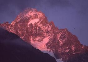 un' montagna picco è illuminato su di il sole foto