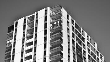 frammento di il di edificio facciata con finestre e balconi. moderno appartamento edifici su un' soleggiato giorno. facciata di un' moderno Residenziale costruzione. nero e bianca. foto
