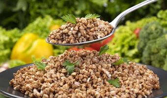 cucinato grano saraceno porridge, servito con erbe aromatiche e verdure su nero piatto foto