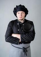 chef maschio che tiene una casseruola isolata su sfondo grigio foto