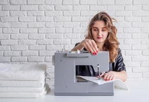 donna che cuce vestiti alla macchina per cucire a casa foto