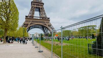 turisti e gente del posto godere un' primavera giorno vicino il eiffel Torre nel Parigi, Francia, con sicurezza scherma nel posto, su aprile 14, 2024, Perfetto per viaggio e europeo cultura temi foto