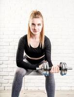 giovane donna sportiva che tiene un manubrio che allena i suoi bicipiti