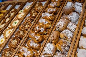 un' lotto di dolce pasticcini nel cesti su il contatore nel il cibo negozio. forno su il buffet tavolo. attività commerciale colazioni e ristorazione a eventi. vario pane genere su ripiano. avvicinamento. selettivo messa a fuoco. foto