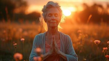 come il sole imposta dietro a sua un' anziano yogi trova interno pace e benessere come lei pratiche yoga all'aperto circondato di il bellezza di natura foto