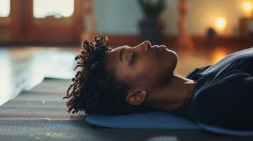 un Immagine di un' persona dire bugie su un' yoga stuoia in profondità respirazione come essi allungare loro muscoli e promuovere in profondità fazzoletto di carta rilassamento attraverso yoga la pratica. foto