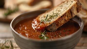 un' fetta di oliva e erba pane essere immerso in un' ciotola di fatti in casa pomodoro la minestra perfettamente complementare il sapori e textures foto