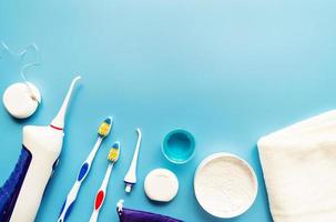 strumenti dentali, filo interdentale, irrigatore della bocca, spazzolini da denti e vista dall'alto di polvere di denti su sfondo blu foto
