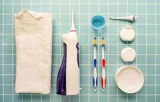 strumenti dentali, filo interdentale, irrigatore della bocca, spazzolini da denti e vista dall'alto di polvere di denti su sfondo blu foto