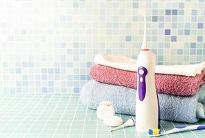 irrigatore elettronico per denti, spazzolini da denti e una pila di asciugamani vista frontale copia spazio