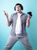 giovane scioccato che gioca ai videogiochi in possesso di un joystick isolato su sfondo blu foto