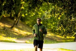 giovane atletico che corre mentre si allena nel soleggiato parco verde