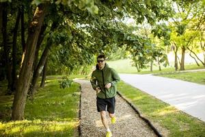 giovane atletico che corre mentre si allena nel soleggiato parco verde foto