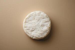 totale ruota di Brie formaggio posto centralmente su un' delicato beige per crema pendenza sfondo, elegante e minimalista foto