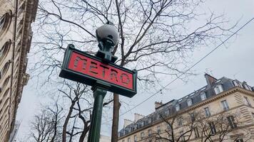 iconico parigino la metropolitana cartello contro un' fondale di primavera spoglio alberi e haussmanniano edifici, catturato nel Parigi, Francia, su aprile 14, 2024, per viaggio e urbano temi foto