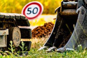 braccio di un' mini scavatrice e secchio con un' velocità limite cartello a 50, strada cartello foto