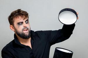 un' barbuto uomo con trucco per Halloween si apre un' nero regalo scatola foto