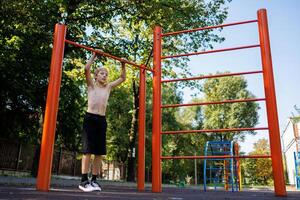 atletico adolescente ottenere pronto per eseguire il esercizio. strada allenarsi su un' orizzontale bar nel il scuola parco. foto