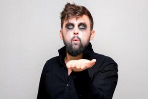 un' uomo con un' barba e non morti trucco su Halloween detiene il suo mani nel davanti di lui foto