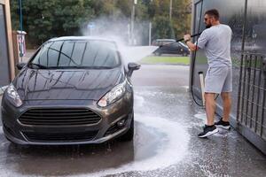 a un' auto lavare, un' uomo lavaggi il suo macchina. un' auto a un' se stesso servizio auto lavare. foto