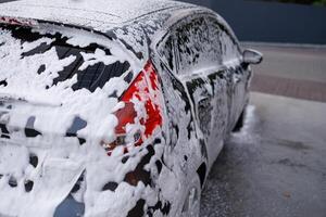 atomico fanale posteriore coperto con lavaggio schiuma. un' auto a un' se stesso servizio auto lavare. foto