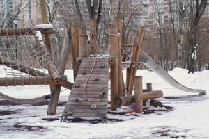 di legno terreno di gioco fatto di naturale eco-friendly Materiale nel pubblico città parco con neve a inverno volta. moderno sicurezza bambini all'aperto attrezzatura. inverno attività. bambini riposo e Giochi su Aperto aria foto