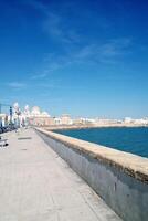 cadice argine panorama con Cattedrale il Santa cruz, grande frangiflutti pietre e atlantico oceano. lungomare Visualizza di cadice. Visualizza di il lungomare banchina andalusia regione, Spagna foto