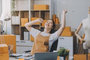 avviare una piccola impresa imprenditoriale o una donna asiatica freelance che utilizza un laptop con scatola, giovane donna asiatica di successo con la mano alzata, scatola di imballaggio e consegna di marketing online, concetto di PMI. foto