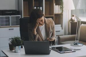 asiatico donne seduta nel un ufficio con fatica e occhio sforzo stanco, ritratto di triste infelice stanco frustrato deluso signora sofferenza a partire dal emicrania seduta a il tavolo, malato lavoratore concetto foto