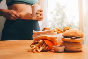 per mangiare o non. triste paffuto donna guardare a il hamburger mentre pensiero per mangiare esso o non foto