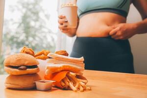 per mangiare o non. triste paffuto donna guardare a il hamburger mentre pensiero per mangiare esso o non foto