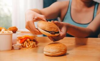 abbuffata mangiare disturbo concetto con donna mangiare veloce cibo hamburger, licenziato pollo , ciambelle e dolci foto