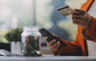 donna è fare in linea acquisti. ragazza è fare shopping utilizzando Telefono e credito carta a casa. foto