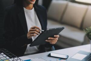 il ritratto di una giovane donna asiatica libera professionista sta lavorando sul tablet del computer in un ufficio moderno. fare un rapporto di analisi contabile dati di investimento immobiliare, concetto di sistemi finanziari e fiscali. foto