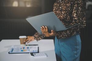 il ritratto di una giovane donna asiatica libera professionista sta lavorando sul tablet del computer in un ufficio moderno. fare un rapporto di analisi contabile dati di investimento immobiliare, concetto di sistemi finanziari e fiscali. foto