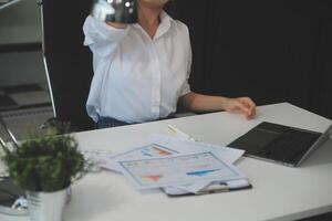 giovane donna asiatica che sente ceppo di testa di emicrania. finanziera donna d'affari stanca e oberata di lavoro mentre lavorava su un computer portatile in ufficio. foto