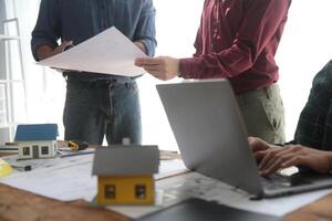 diverso squadra di specialisti uso il computer portatile su costruzione luogo. vero tenuta edificio progetto con ingegnere investitore e uomo d'affari controllo la zona, Lavorando su civile ingegneria, discutere strategia Piano foto