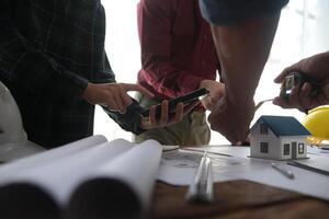 costruzione e struttura concetto di ingegnere o architetto incontro per progetto Lavorando con compagno e ingegneria utensili su modello edificio e planimetria nel Lavorando luogo, contrarre per tutti e due aziende. foto