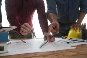 costruzione e struttura concetto di ingegnere o architetto incontro per progetto Lavorando con compagno e ingegneria utensili su modello edificio e planimetria nel Lavorando luogo, contrarre per tutti e due aziende. foto