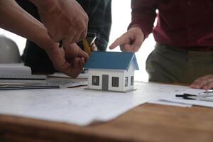 costruzione e struttura concetto di ingegnere o architetto incontro per progetto Lavorando con compagno e ingegneria utensili su modello edificio e planimetria nel Lavorando luogo, contrarre per tutti e due aziende. foto