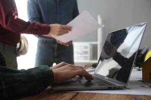 diverso squadra di specialisti uso il computer portatile su costruzione luogo. vero tenuta edificio progetto con ingegnere investitore e uomo d'affari controllo la zona, Lavorando su civile ingegneria, discutere strategia Piano foto