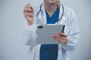 medico indossare bianca cappotto e Guardando paziente dati nel tavoletta . foto