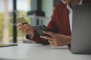 mano Tenere credito carta e utilizzando il computer portatile. donna d'affari o imprenditore Lavorando a partire dal casa. in linea acquisti, commercio elettronico, Internet bancario, la spesa i soldi, opera a partire dal casa concetto foto