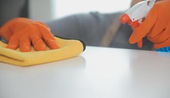 donna pulizia tavolo utilizzando straccio e diffusore a casa. foto