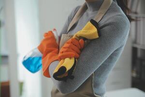 donna pulizia tavolo utilizzando straccio e diffusore a casa. foto